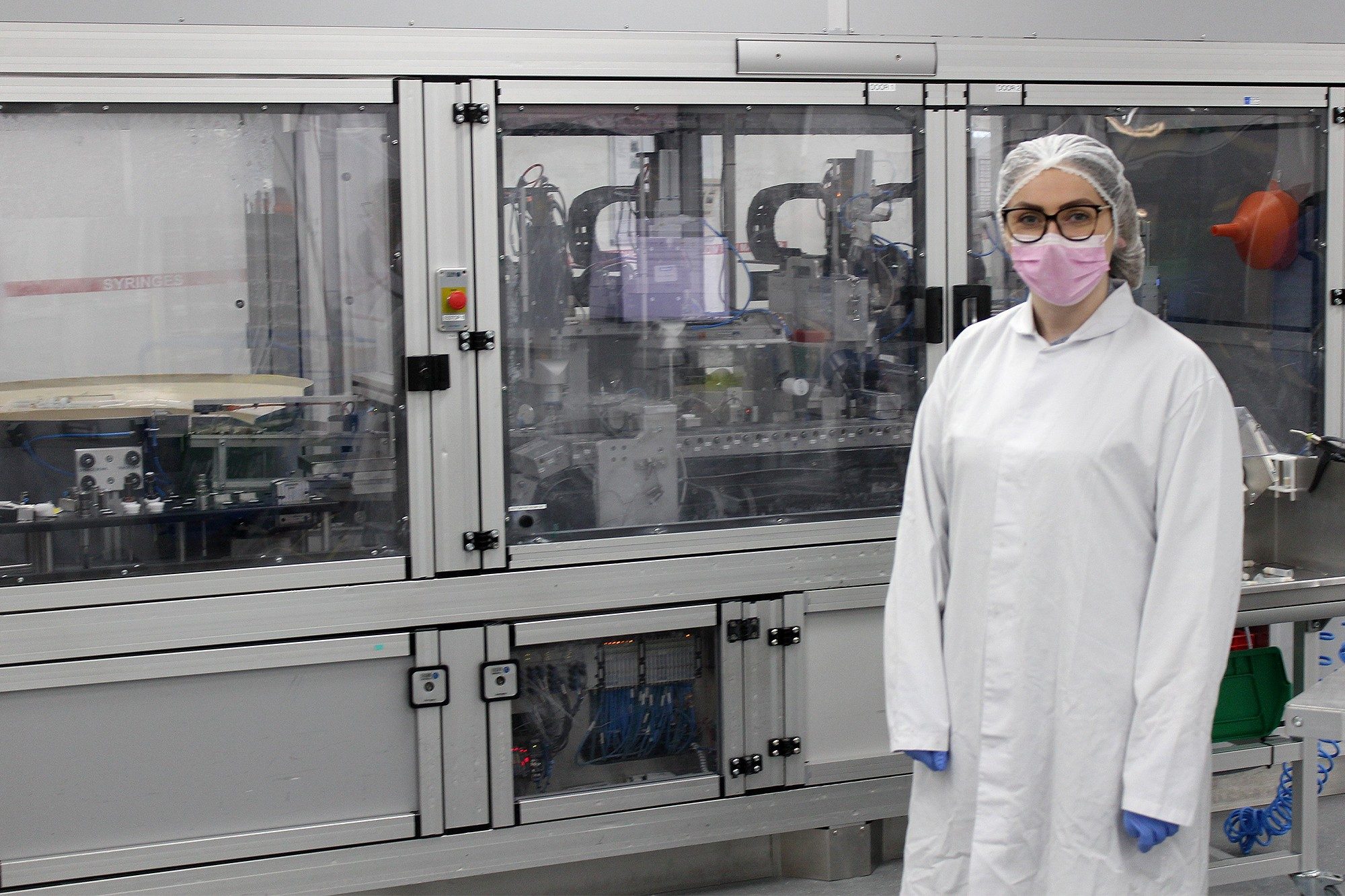 Emma Whelan in Waters Laboratory wearing a labcoat, mask, hairnet, and glasses