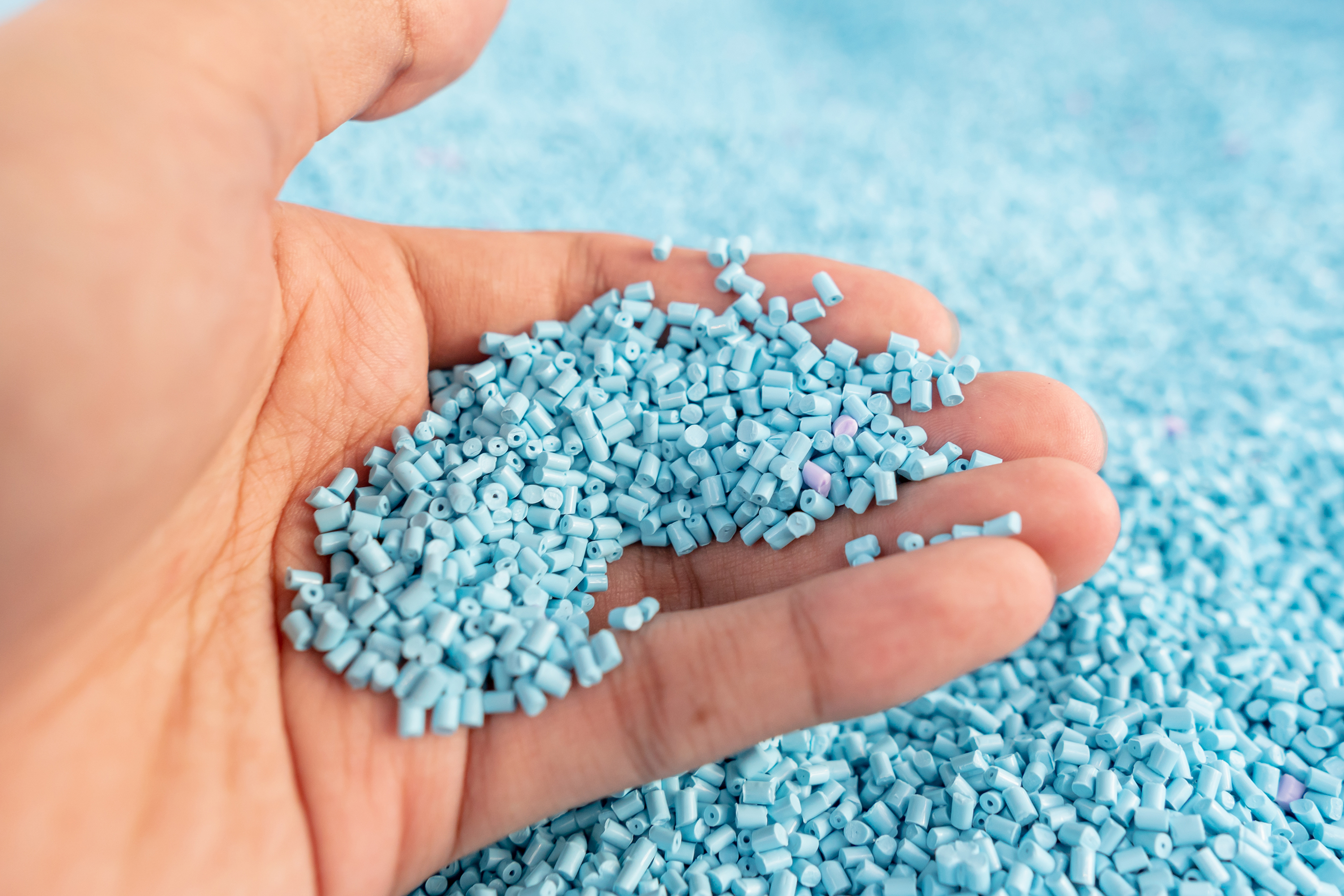 Blue plastic polymer granules in hand