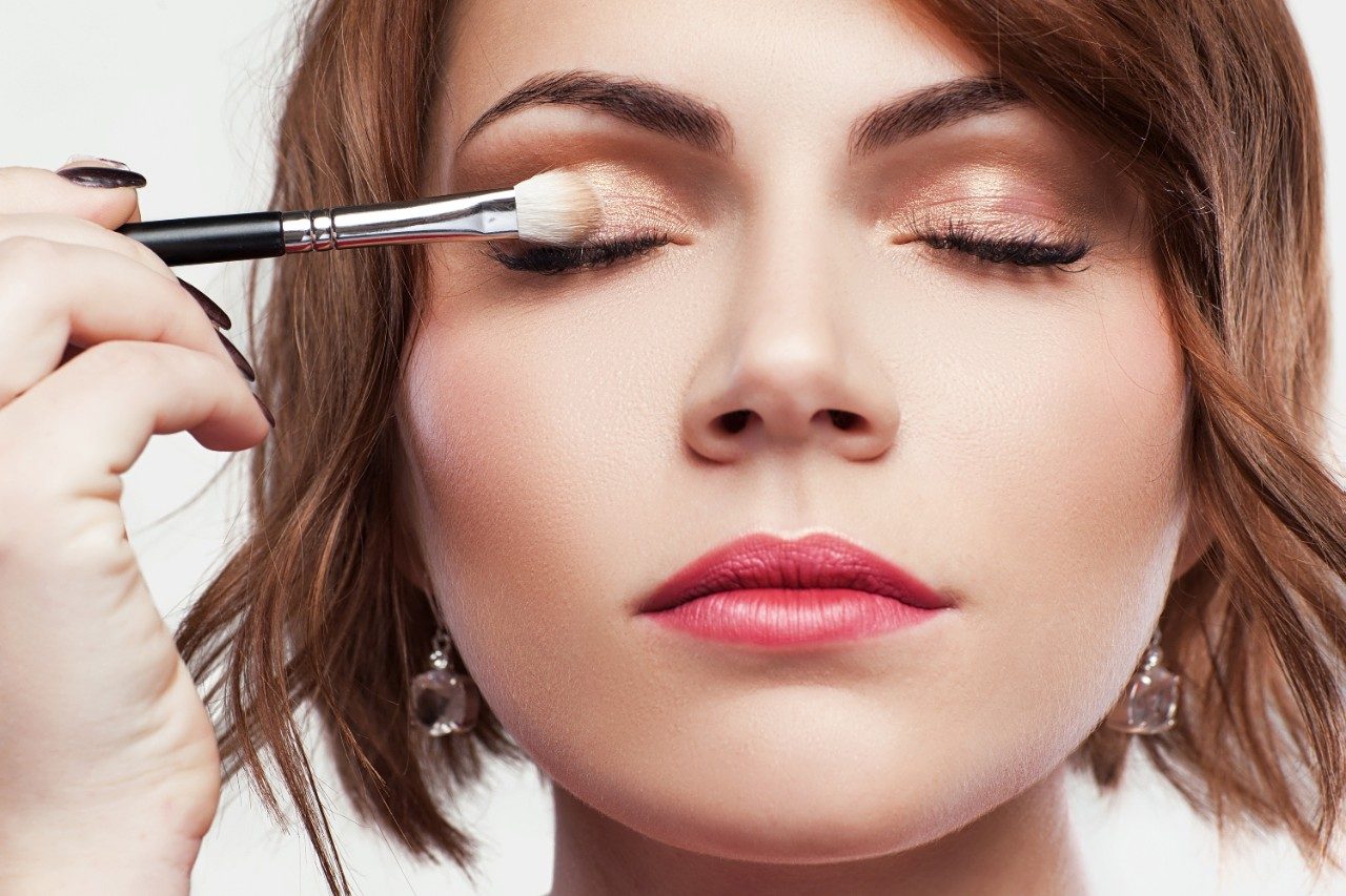 Female applying eyeshadow makeup on face