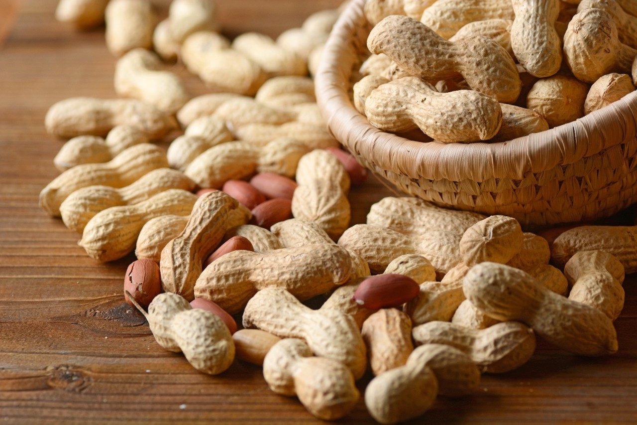 Shelled peanuts in bowl and on wood table