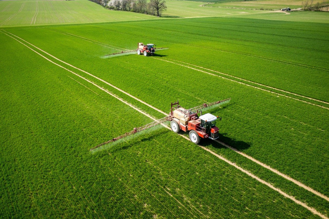 Aerial vew of tractor in field spraying pesticide