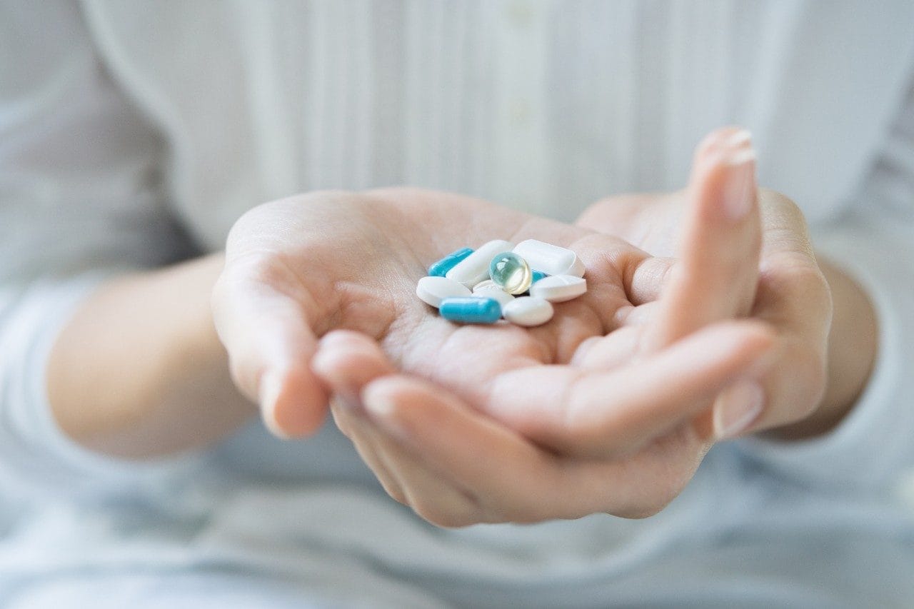 Female holding various pills on hand