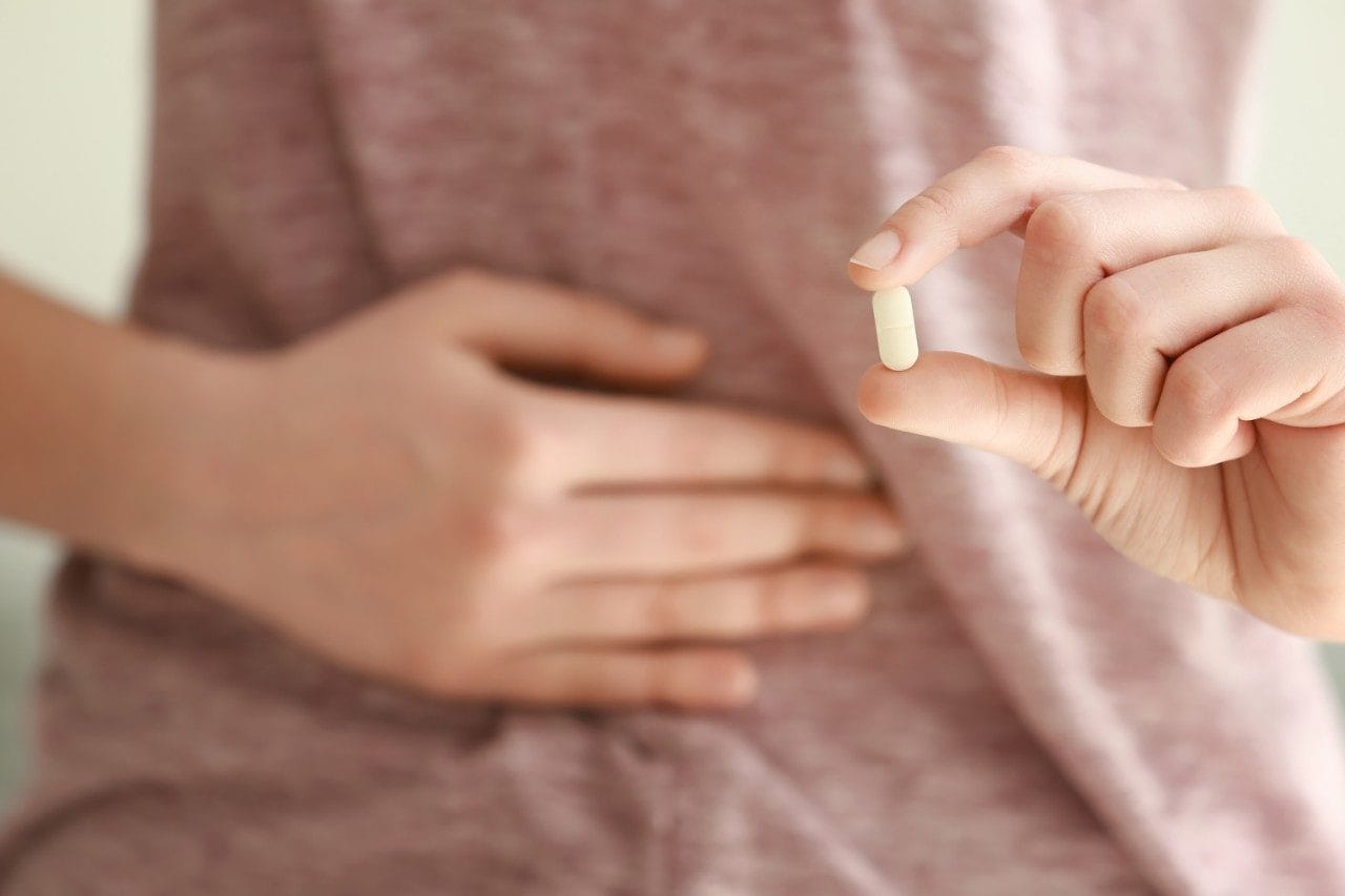 Woman with pill suffering from stomach pain or nausea