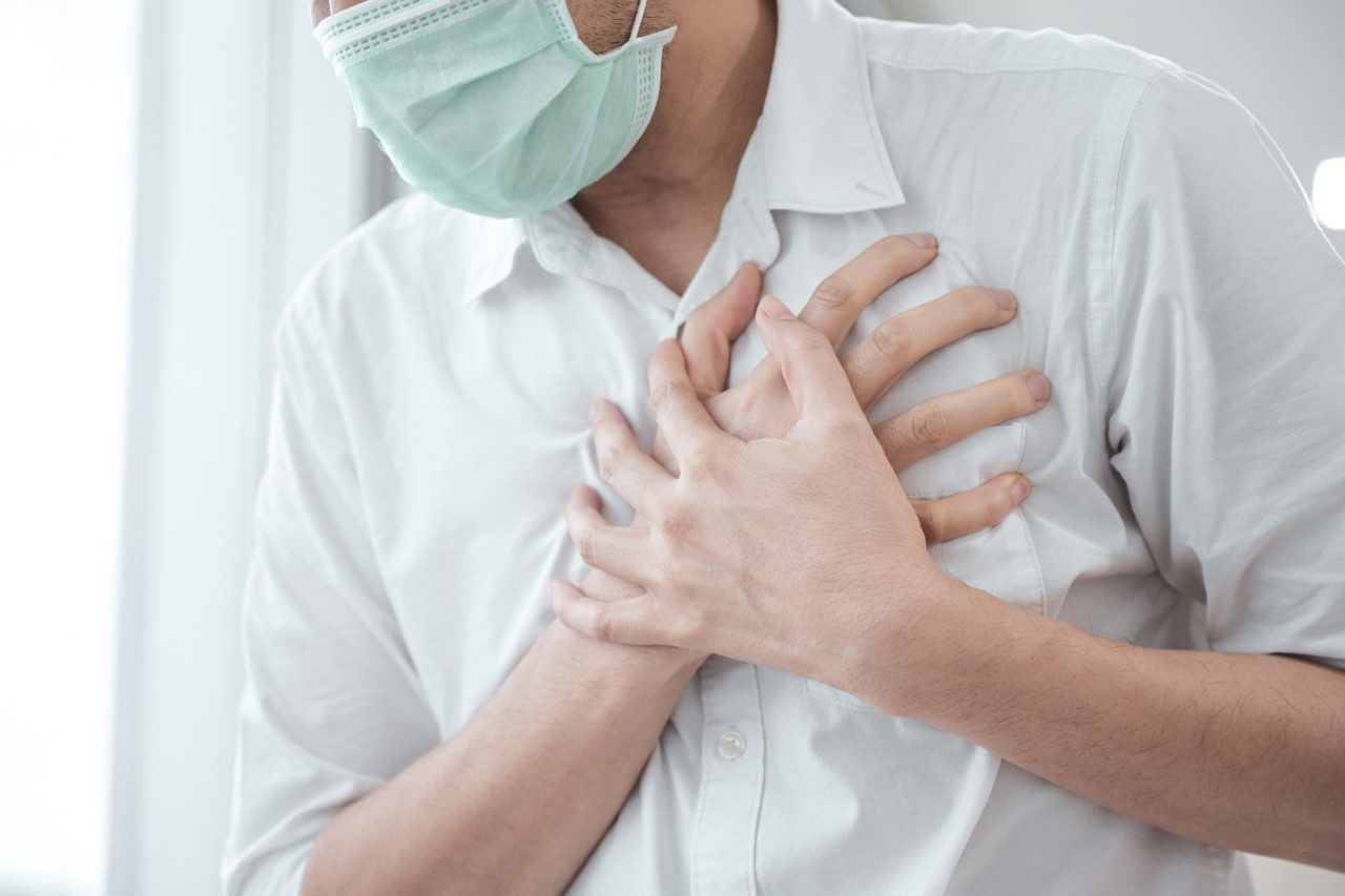 Man in face mask, symptoms of coronavirus diseases, chest pain