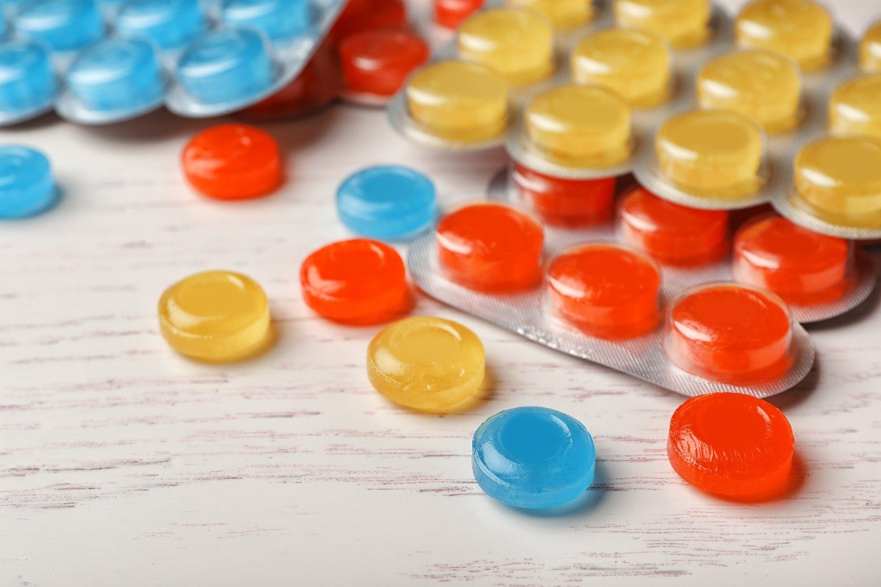 Color cough drops on wooden background