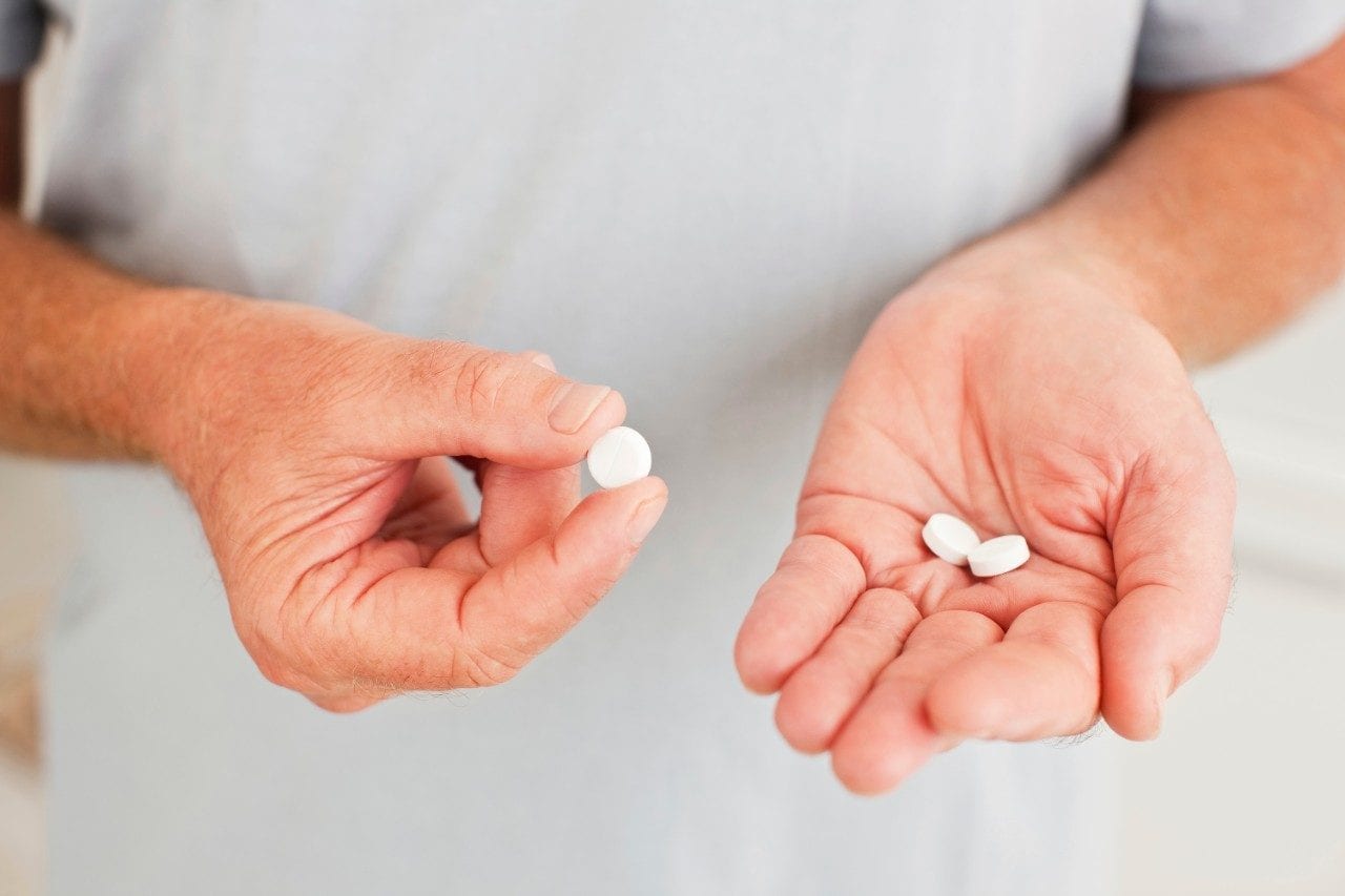 Hands holding white pills