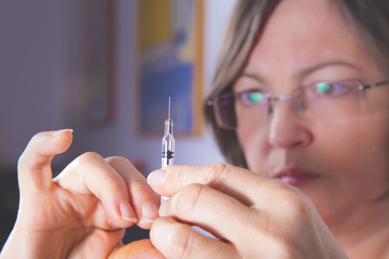 Female preparing syringe for injection