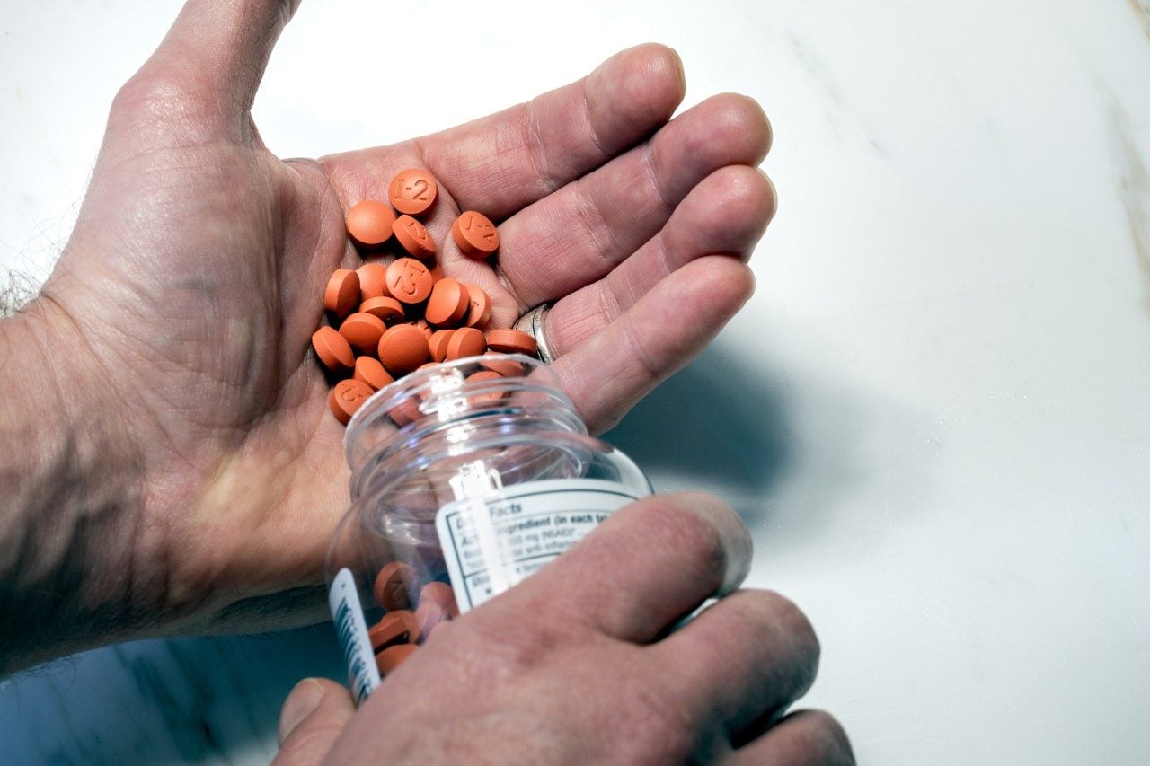 Person pouring pills into hand