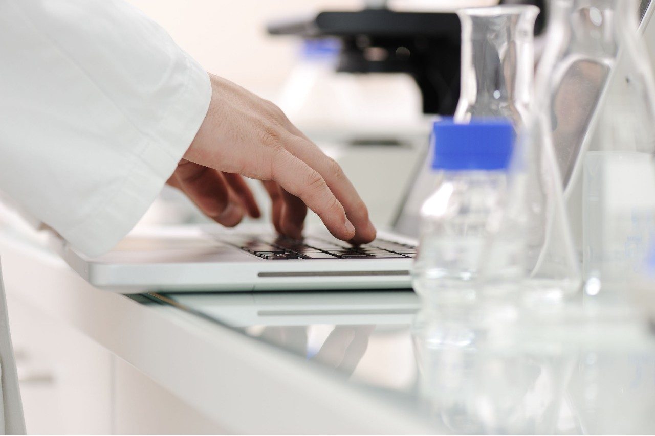 Lab scientist typing on laptop keyboard