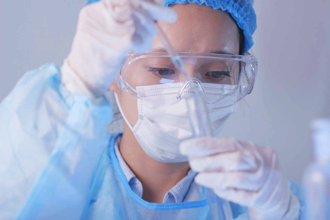 Scientist observing test tube with pipette