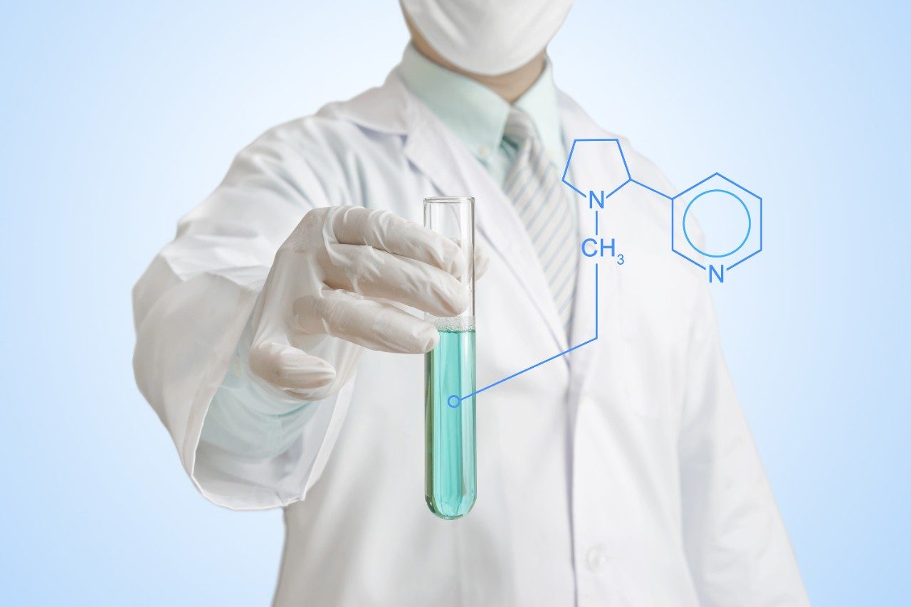 Scientist holding a chemical test tube with chemical formula for nicotine