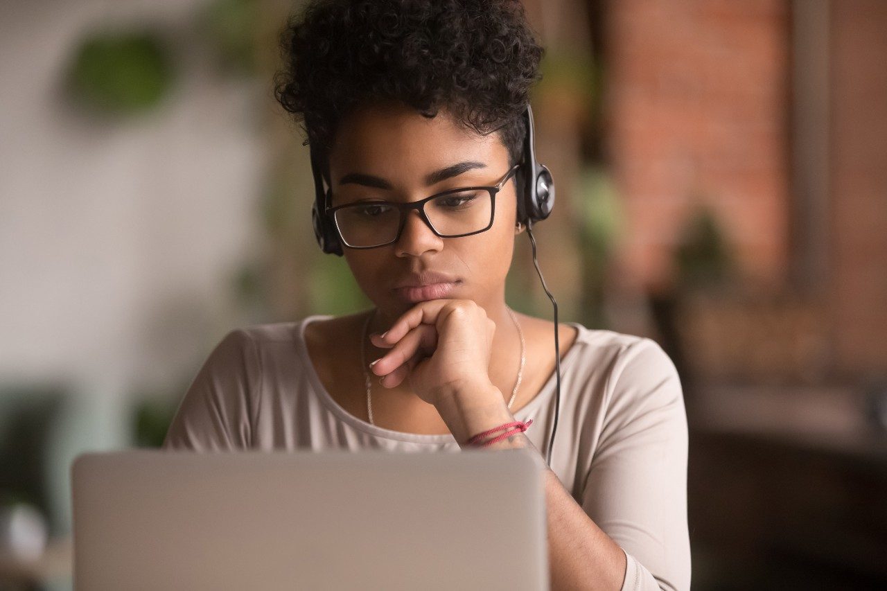 Student wearing headphones watching webinar on laptop