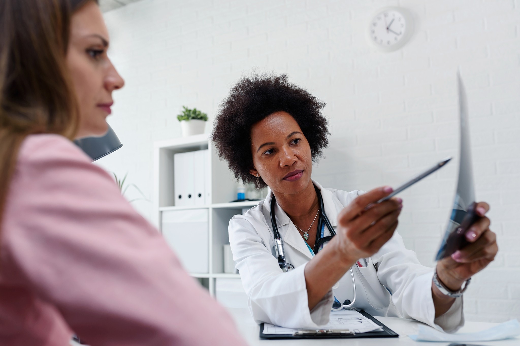 Una médica hablando con una paciente en el escritorio de la consulta médica (Women’s Health)