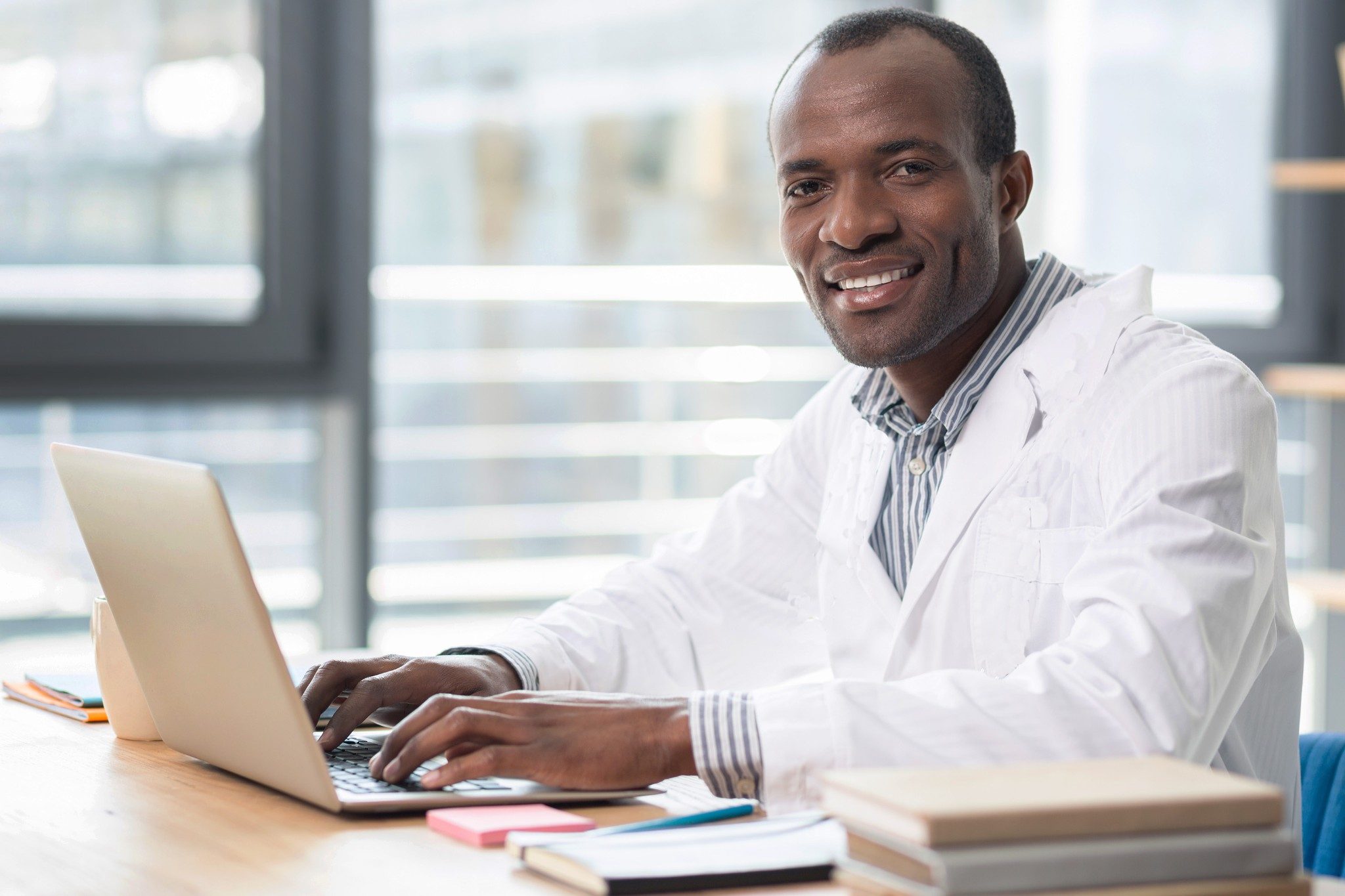 Científico masculino sonriendo mientras está en la computadora