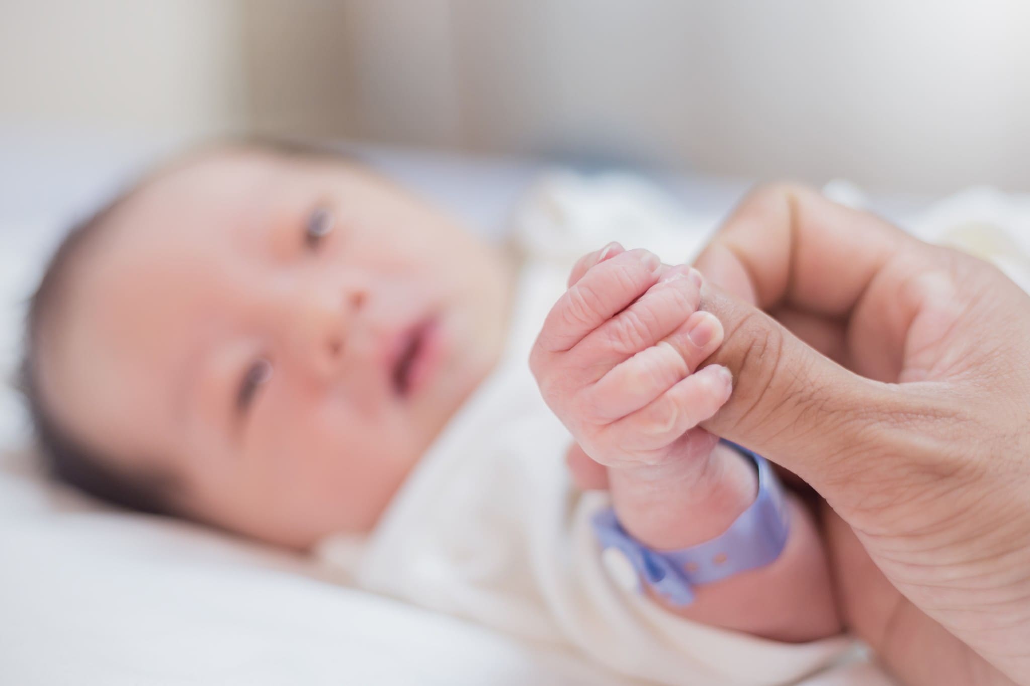 Mão segurando os dedos de um bebê recém-nascido